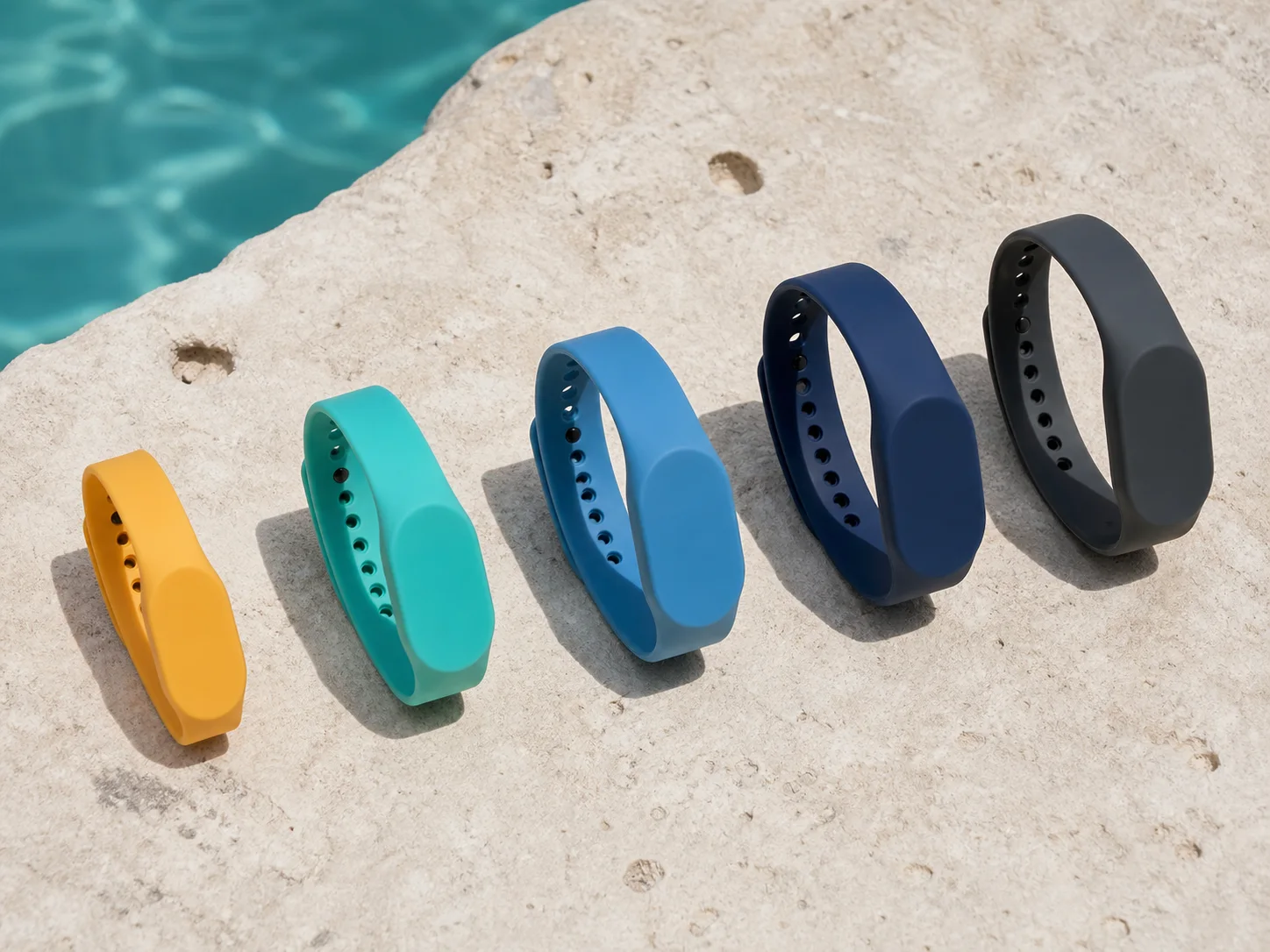 Five silicone RFID wristband sizes arranged on pale limestone